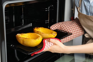 Photo of Woman taking baked spaghetti squash out of oven, closeup