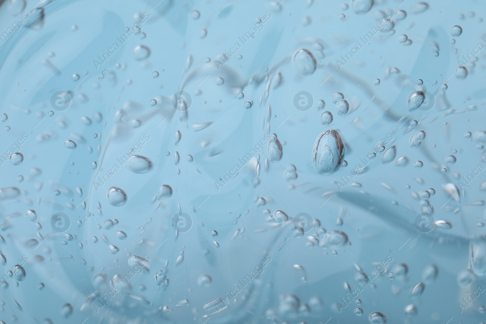 Photo of Pure transparent cosmetic gel on light blue background, closeup