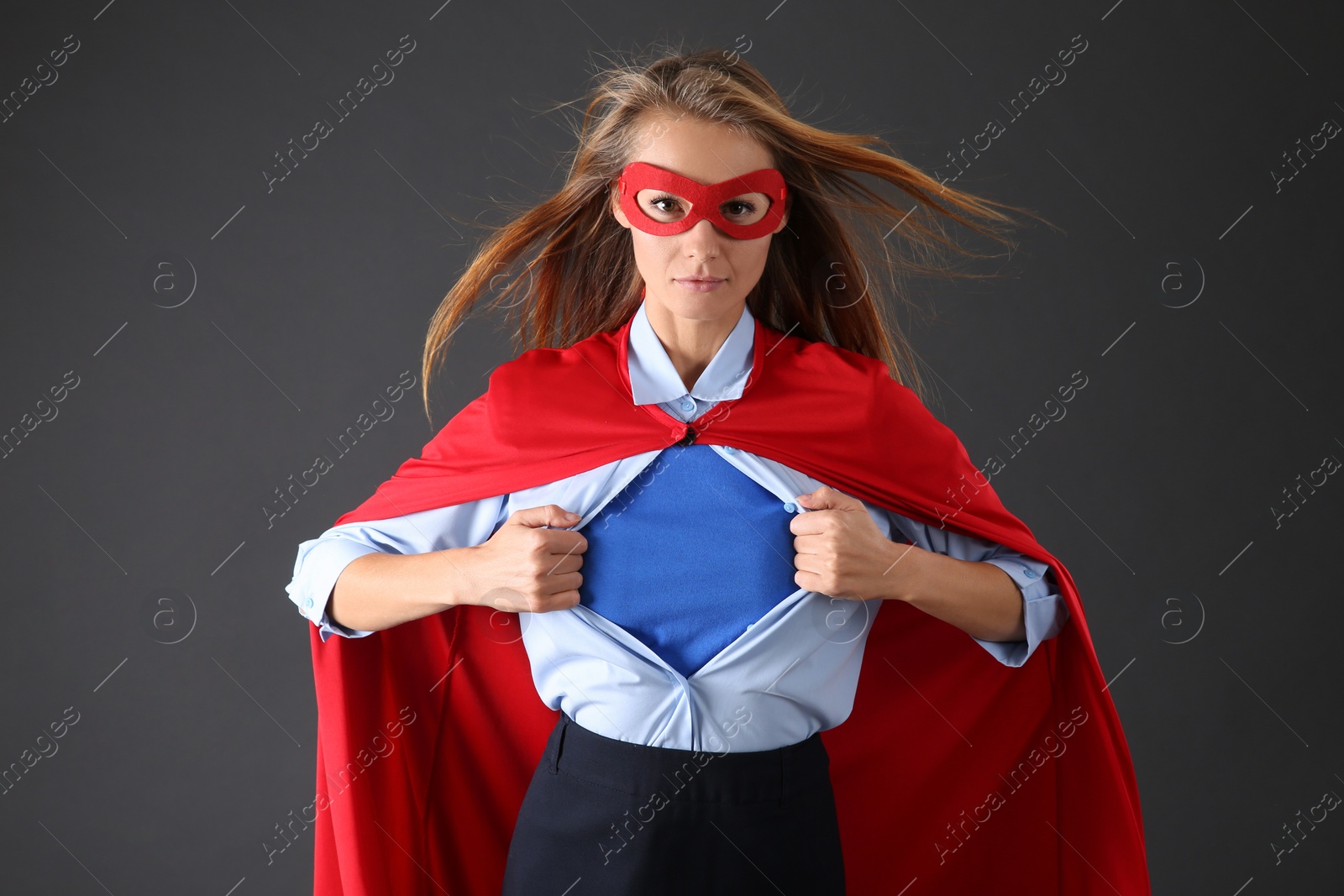 Photo of Confident businesswoman wearing superhero costume under suit on grey background