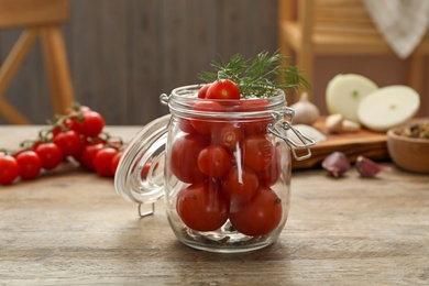 Pickling jar with fresh tomatoes on wooden kitchen table