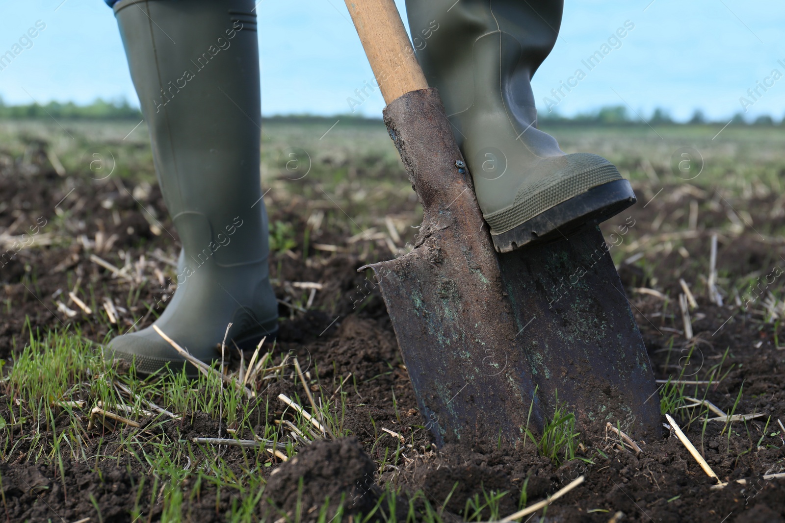 Photo of Man digging soil with shovel in field, closeup