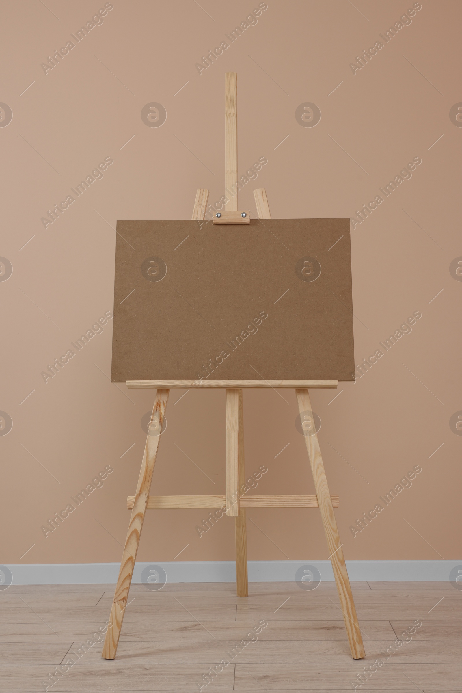 Photo of Wooden easel with blank board near beige wall indoors