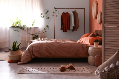 Photo of Bed with orange and brown linens in stylish room interior