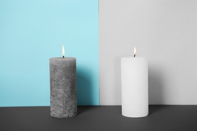 Photo of Decorative wax candles on table against color background