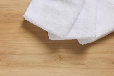 Photo of Soft folded terry towels on wooden table, top view. Space for text