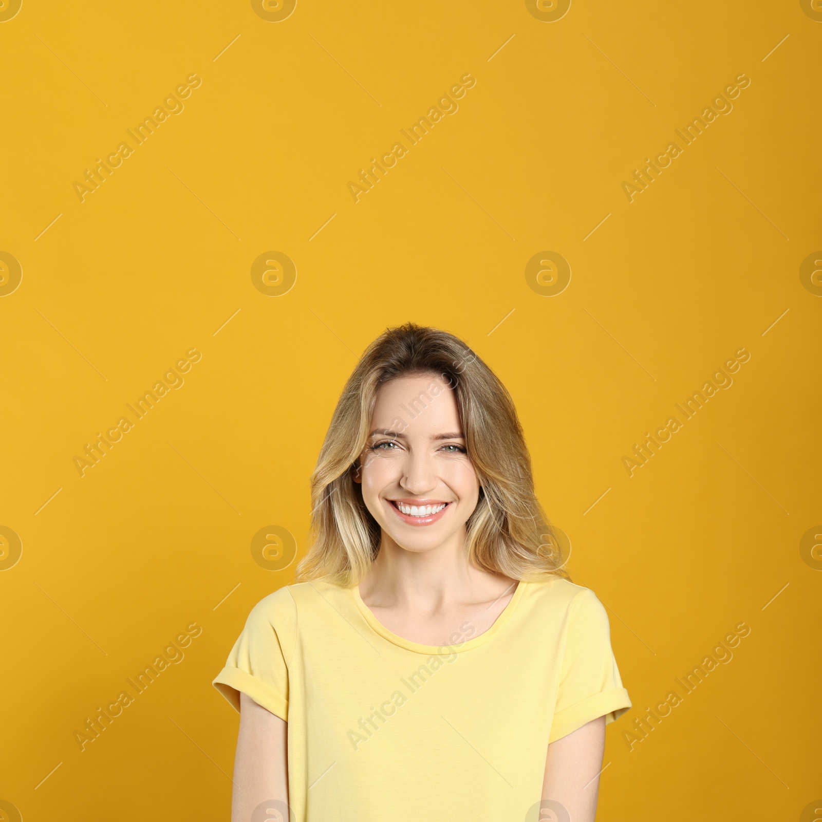 Photo of Portrait of happy young woman with beautiful blonde hair and charming smile on yellow background