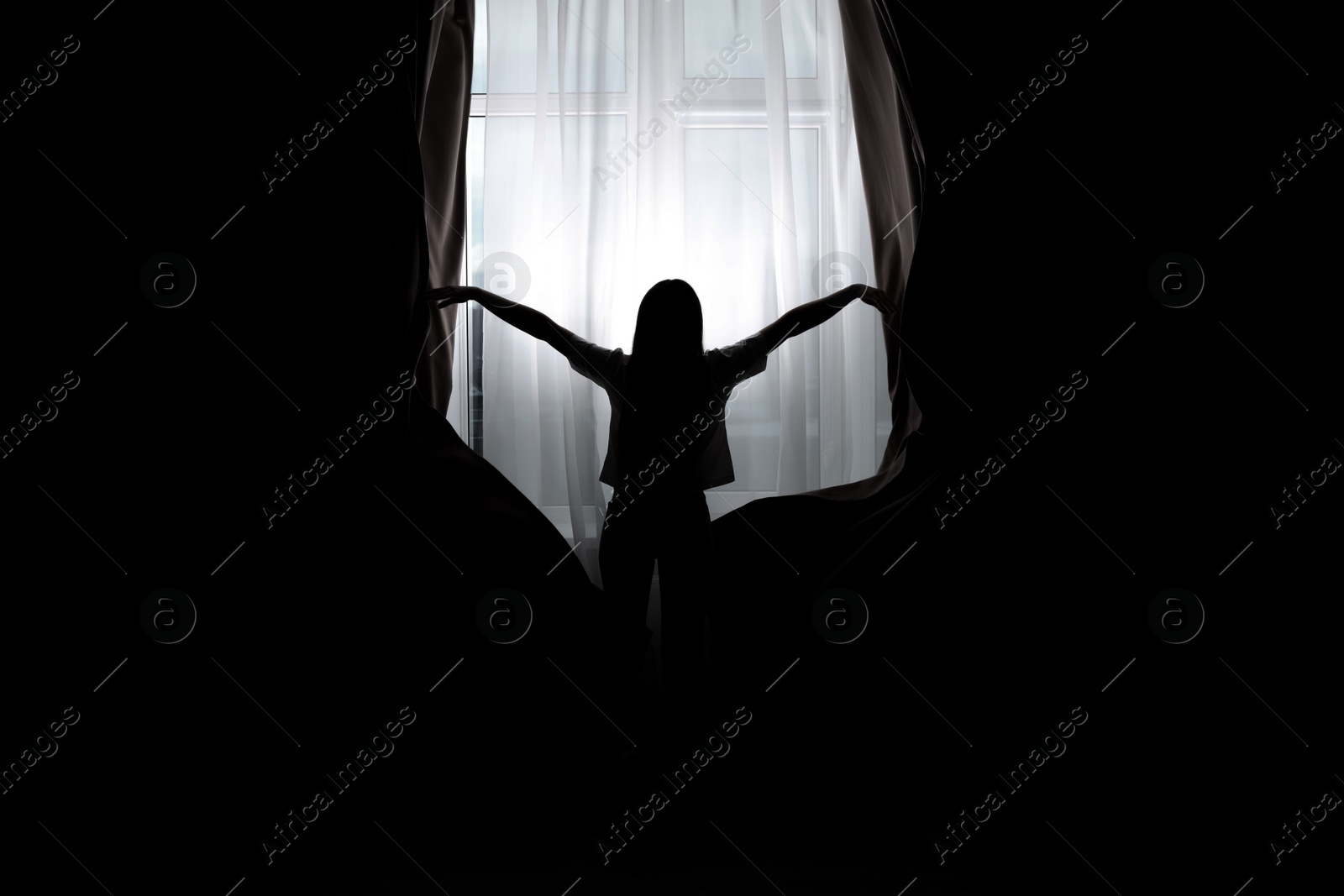Image of Silhouette of woman opening curtains at home, back view