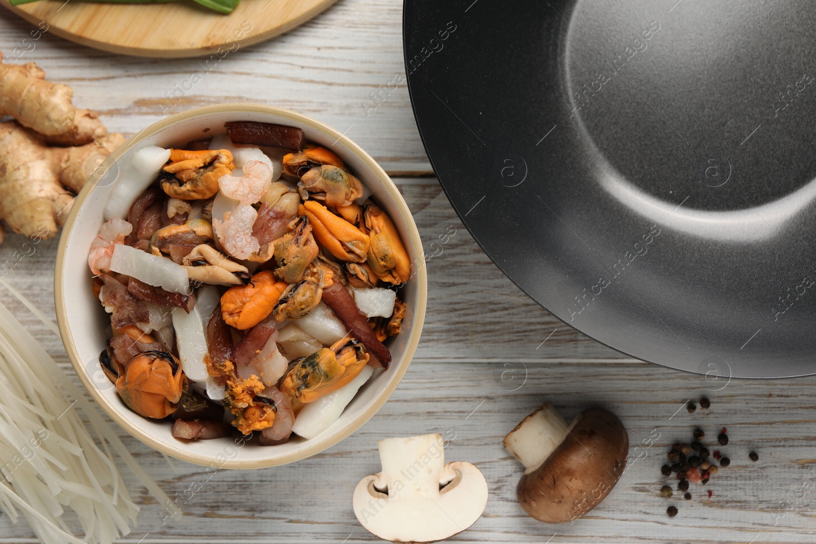 Photo of Flat lay composition with black wok and products on light wooden table