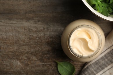 Photo of Jar of delicious mayonnaise and fresh spinach on wooden table, flat lay. Space for text