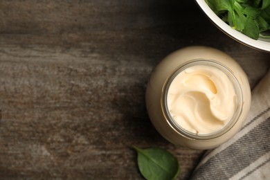 Jar of delicious mayonnaise and fresh spinach on wooden table, flat lay. Space for text