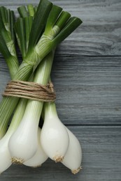 Photo of Bunch of green spring onions on grey wooden table, flat lay