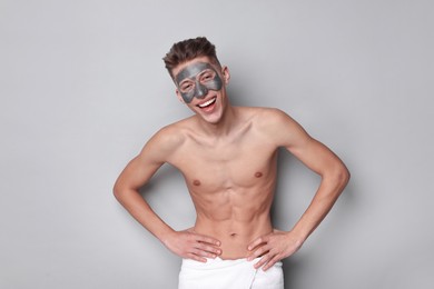 Handsome man with clay mask on his face against light grey background