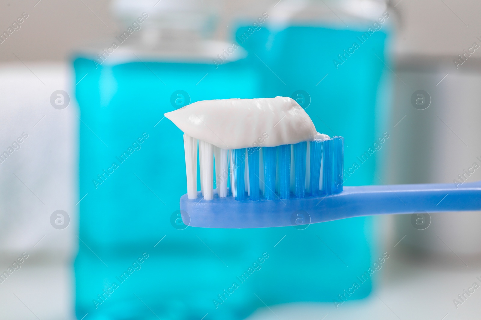 Photo of Toothbrush with paste near mouthwash on blurred background, closeup