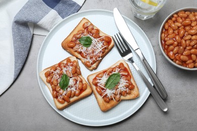 Photo of Toasts with delicious canned beans on light grey table, flat lay