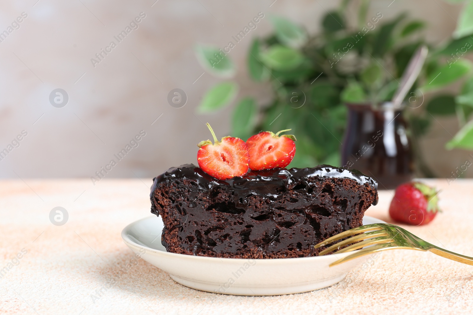 Photo of Piece of chocolate sponge cake with strawberry on beige textured table