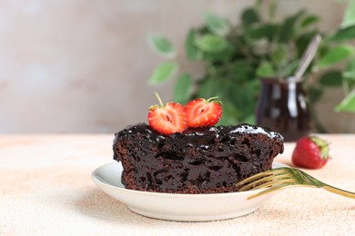 Piece of chocolate sponge cake with strawberry on beige textured table