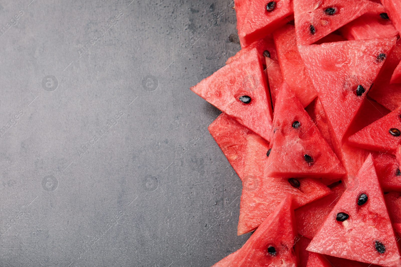 Photo of Delicious fresh watermelon slices on grey table, flat lay. Space for text