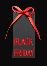 Tag with phrase BLACK FRIDAY on dark background, top view