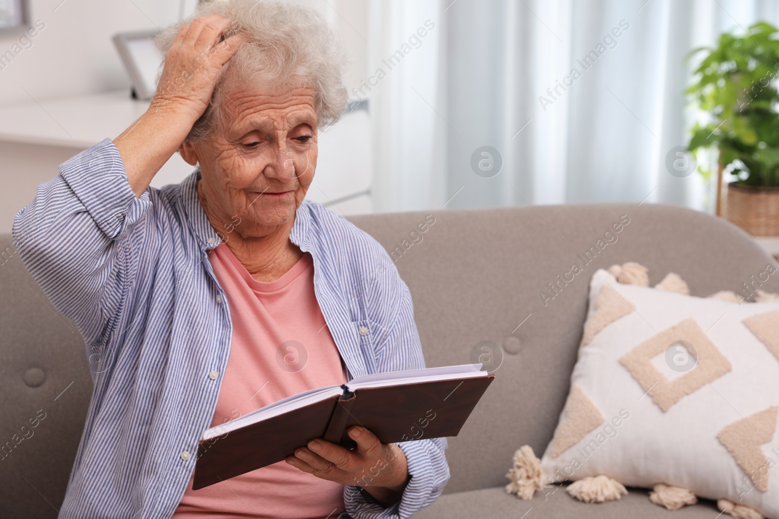 Photo of Senior woman with notebook at home, space for text. Age-related memory impairment