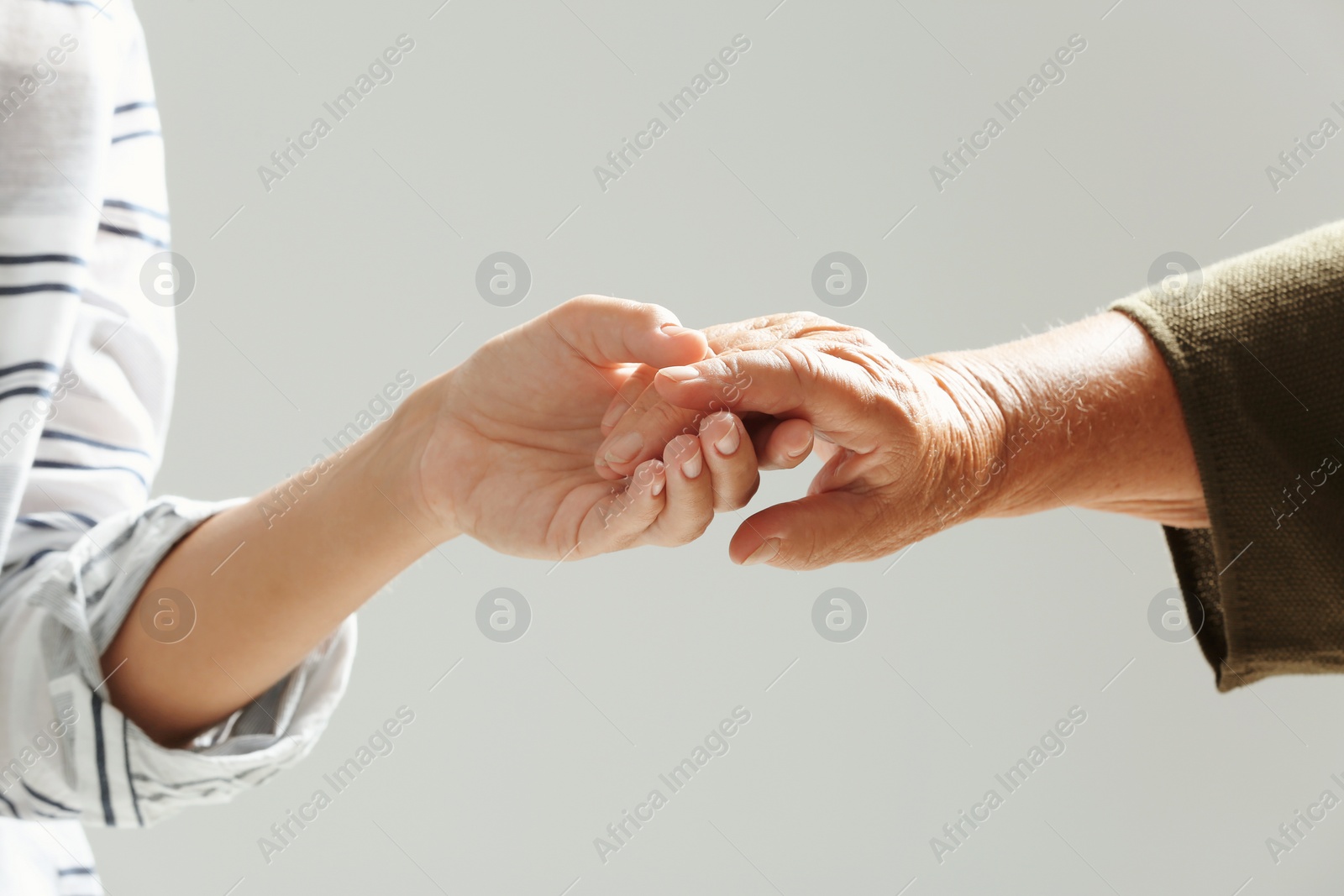 Photo of Helping hands on gray background, closeup. Elderly care concept