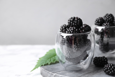 Photo of Delicious fresh ripe blackberries in glass on white table. Space for text