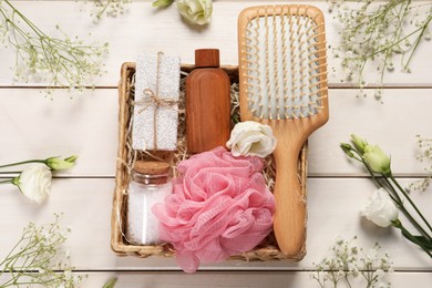 Photo of Spa gift set with different products in wicker box on white wooden table, flat lay