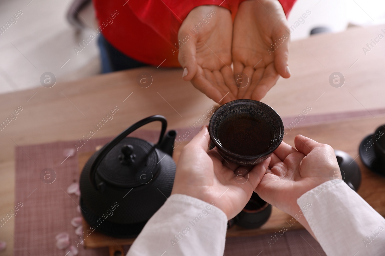 Photo of Master giving freshly brewed tea to guest during ceremony at table, closeup