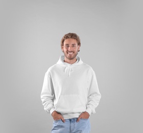 Portrait of man in hoodie sweater on light background. Space for design