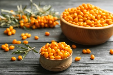 Photo of Ripe sea buckthorn berries on grey wooden table, closeup