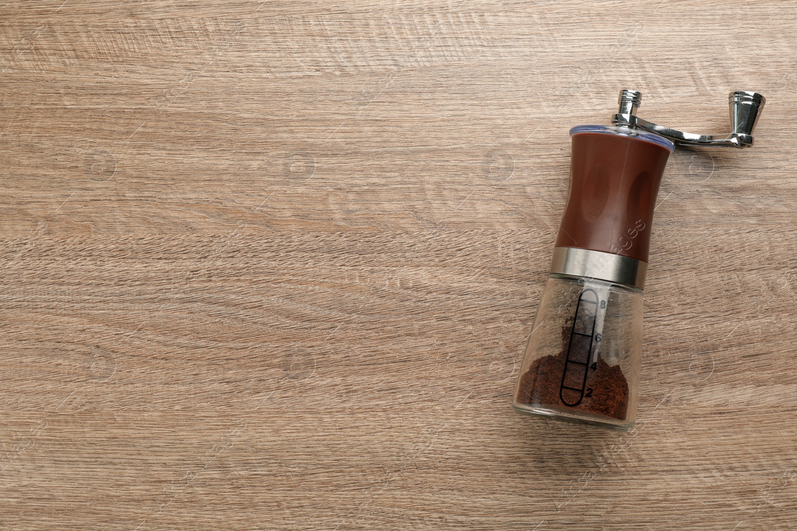 Photo of Modern manual coffee grinder on wooden table, top view. Space for text