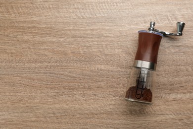 Modern manual coffee grinder on wooden table, top view. Space for text