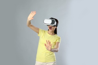 Woman using virtual reality headset on grey background