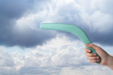 Woman holding boomerang against cloudy sky, closeup 