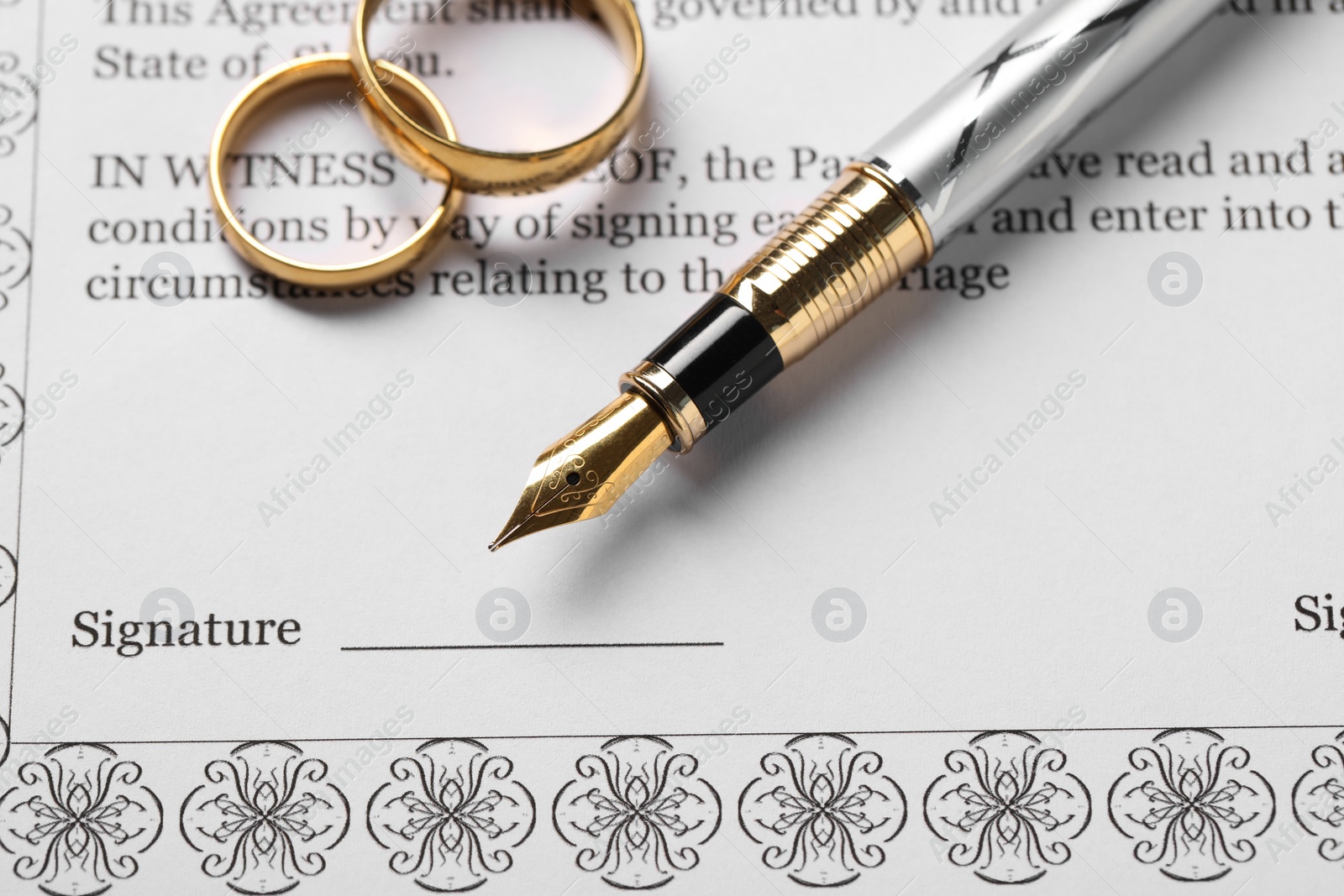 Photo of Marriage contract, gold rings and pen on table, top view