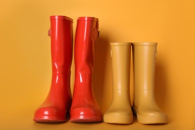 Photo of Two pairs of rubber boots on orange background