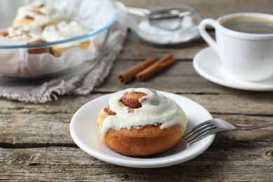 Photo of Tasty cinnamon roll with cream on wooden table. Space for text