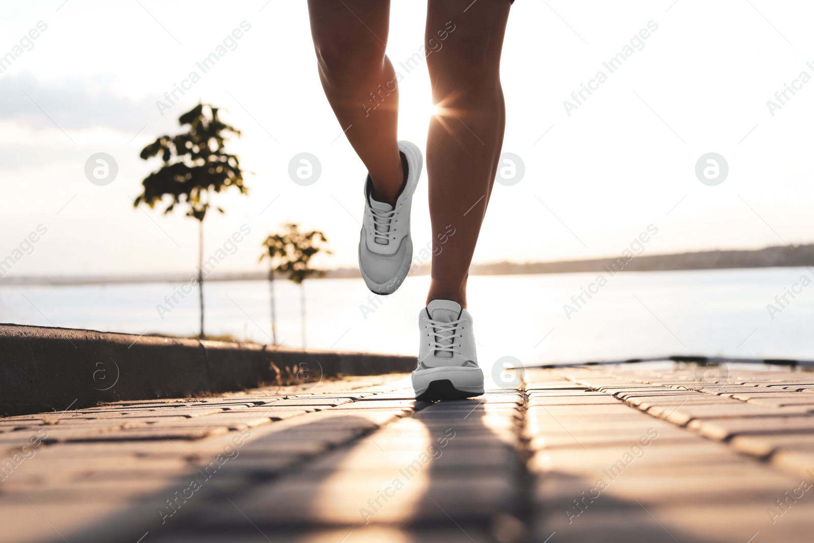 Photo of Young woman running near river in morning, closeup