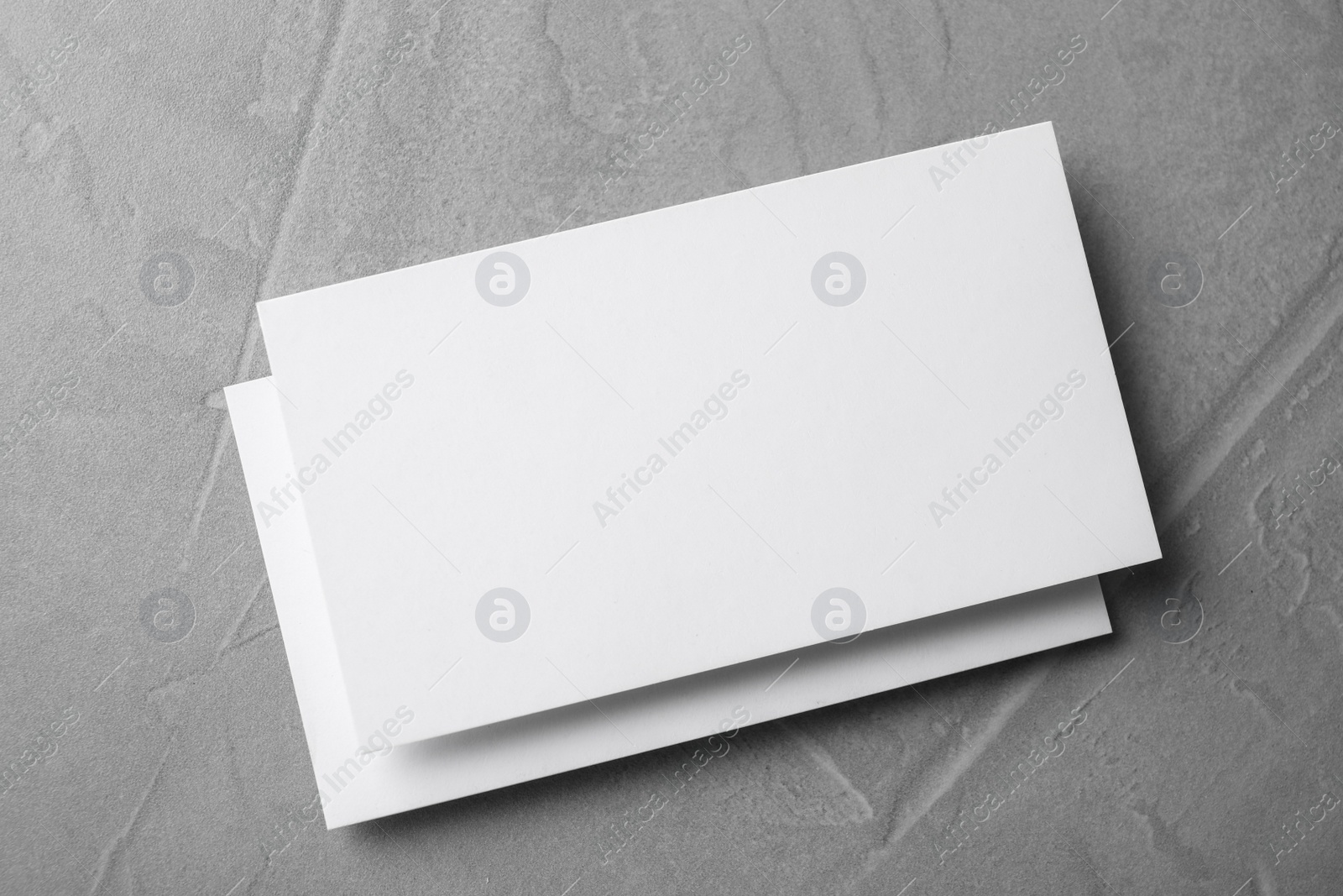 Photo of Blank business cards on light grey stone background, top view. Mock up for design