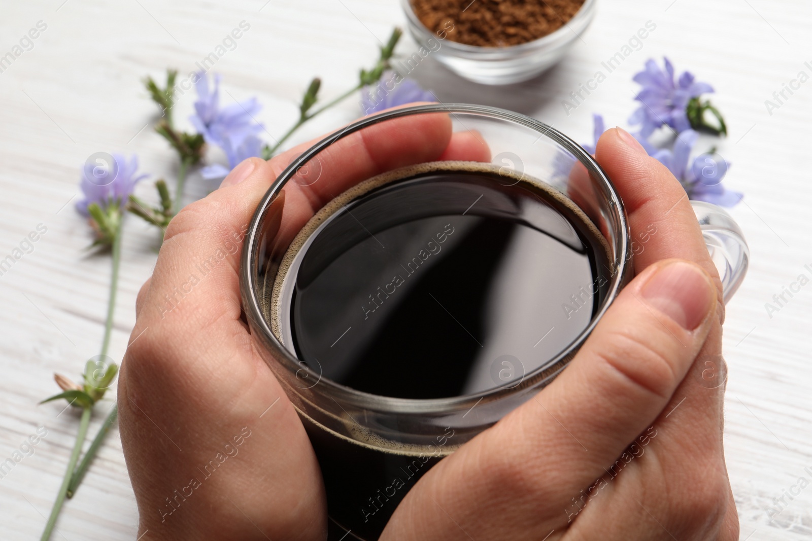 Photo of Woman holding cup of delicious chicory drink at white table, closeup