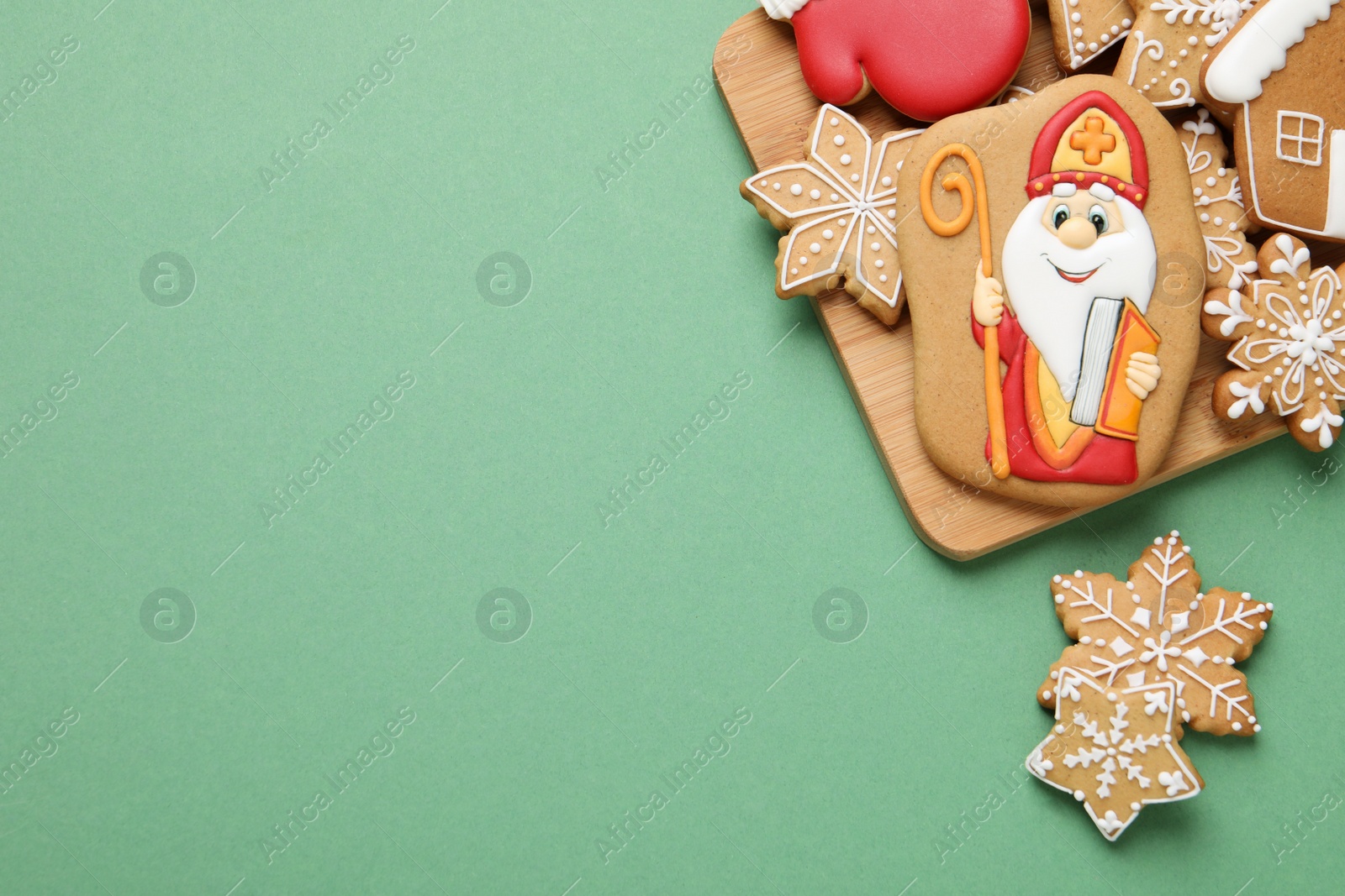 Photo of Tasty gingerbread cookies on green background, flat lay with space for text. St. Nicholas Day celebration