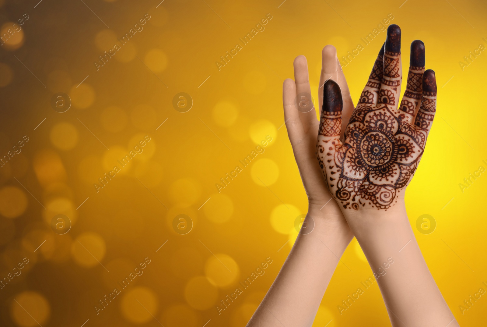 Image of Woman with henna tattoo on palm against blurred lights, bokeh effect. Space for text