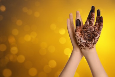 Image of Woman with henna tattoo on palm against blurred lights, bokeh effect. Space for text