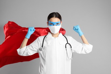Doctor dressed as superhero posing on light grey background. Concept of medical workers fighting with COVID-19