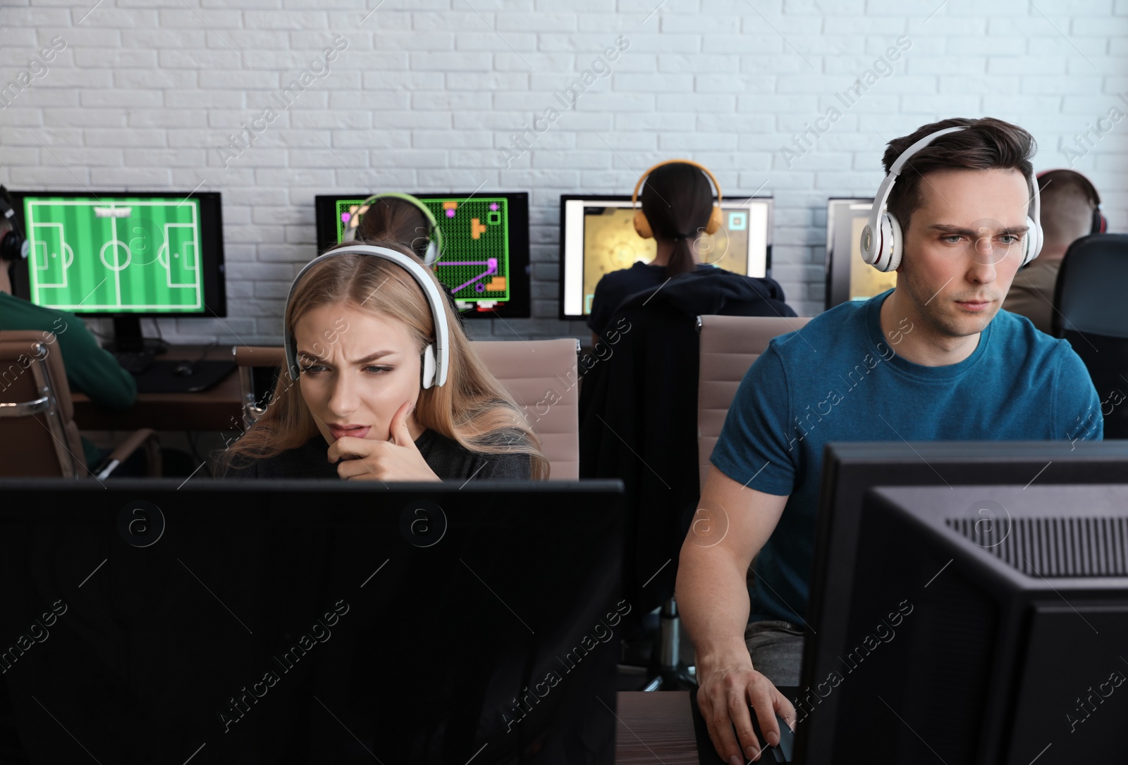 Photo of Young people playing video games on computers indoors. Esports tournament