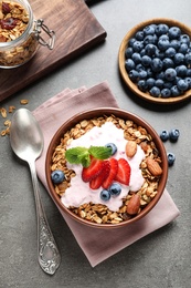 Delicious yogurt with granola and berries served on grey table, flat lay