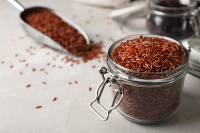 Photo of Brown rice in glass jar on table. Space for text