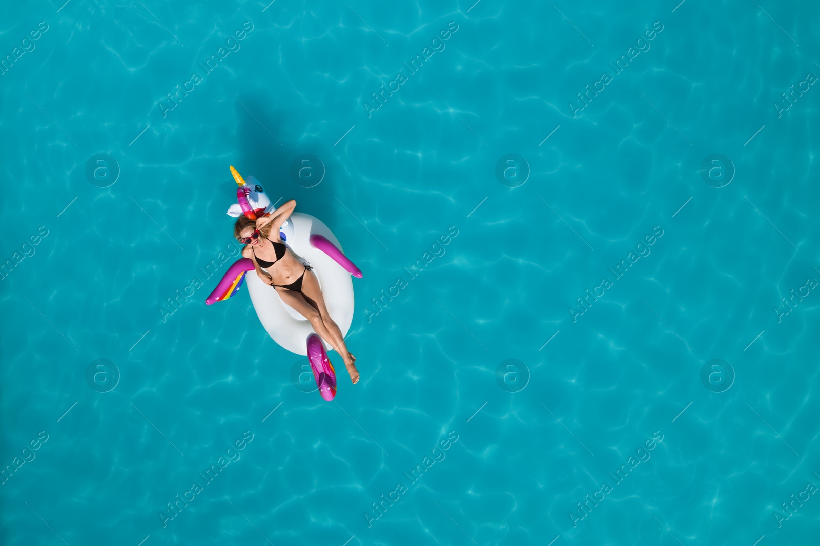 Image of Young happy woman with inflatable ring in swimming pool, top view and space for text. Summer vacation