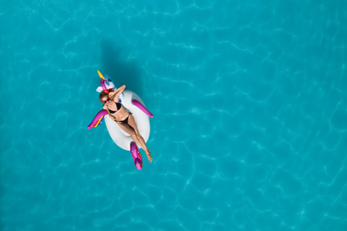 Image of Young happy woman with inflatable ring in swimming pool, top view and space for text. Summer vacation