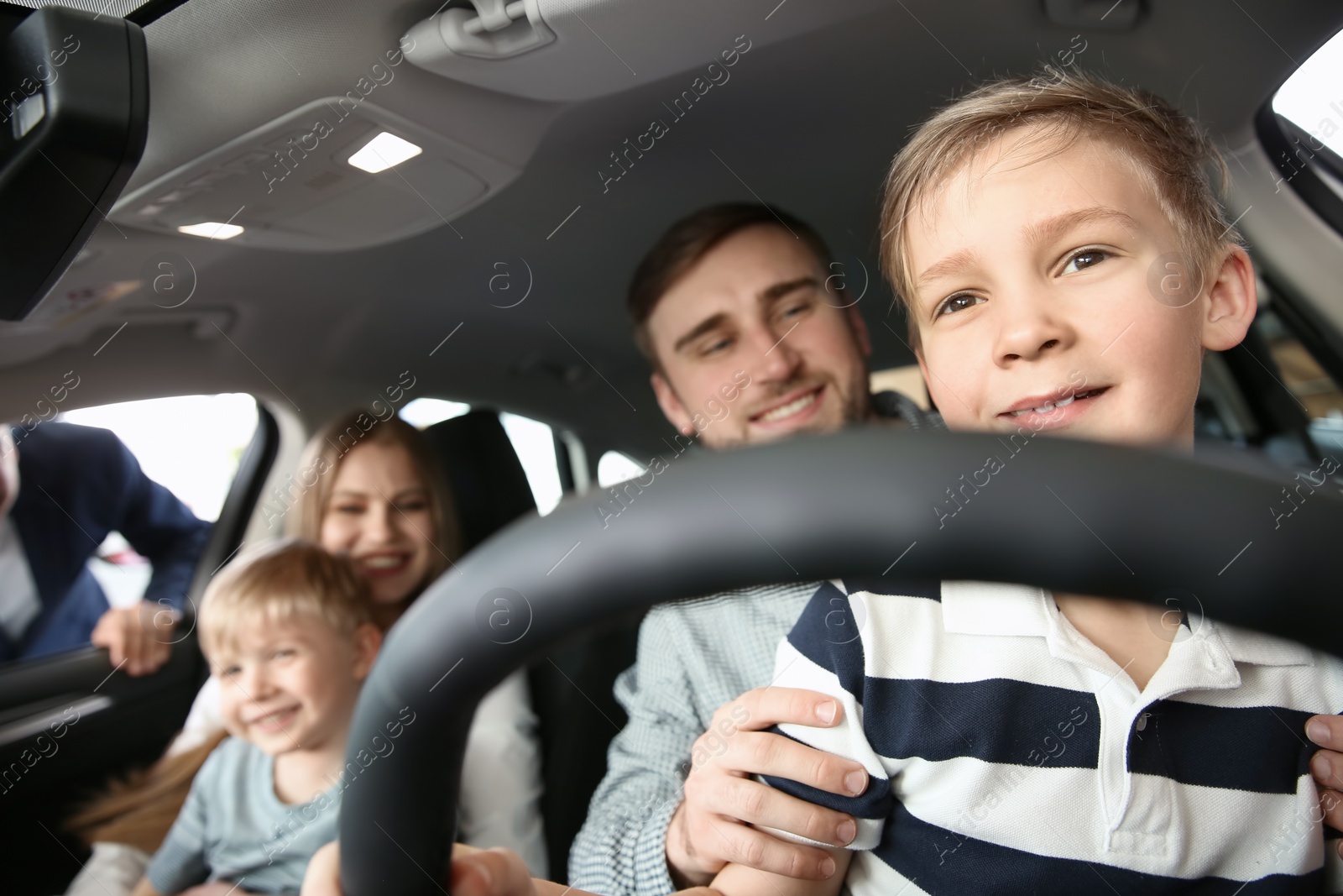 Photo of Young family choosing new car with salesman in salon