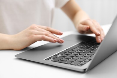 Photo of E-learning. Woman using laptop at white table indoors, closeup